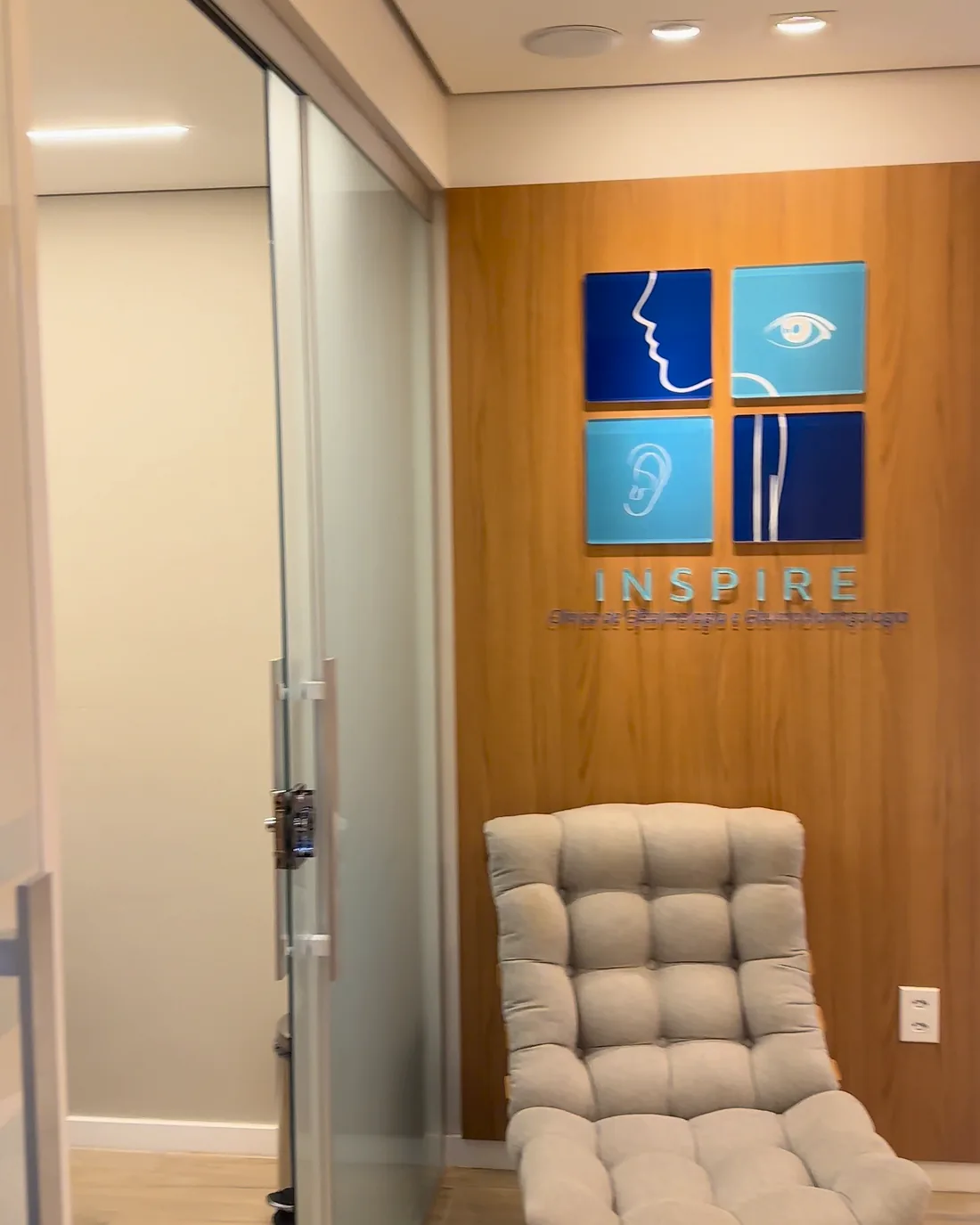 Recepção da Clínica Inspire com painel da marca em madeira e poltrona